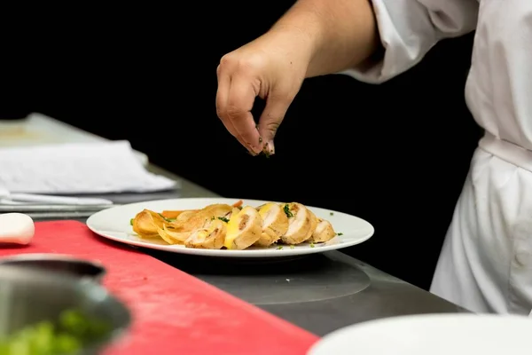 A chief adding seasonings on the food in a restaurant