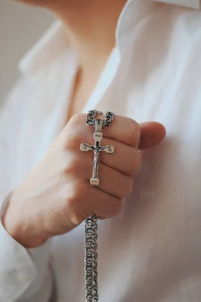 一个宗教男子拿着一条镶有十字坠的银项链的特写镜头 — 图库照片
