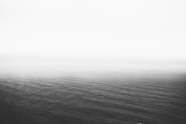 Uma Imagem Escala Cinza Oceano Calmo Desaparecendo Lentamente Horizonte Perfeito — Fotografia de Stock