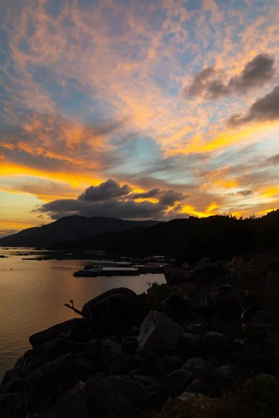 美丽的夕阳西下的天空笼罩着一个岩石海岸和山脉轮廓的海湾 — 图库照片