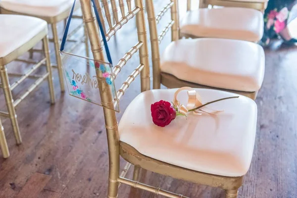 一枝红玫瑰的特写镜头放在大厅里整个椅子的金色椅子上 — 图库照片