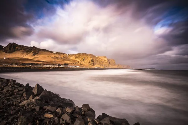 アイスランドを背景にした丘のある穏やかな湖の岩場の海岸の魅惑的な景色 — ストック写真