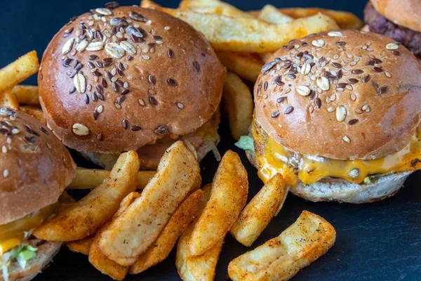 Zbliżenie Pysznych Frytek Hamburgerów Zwieńczonych Nasionami Czarnej Fakturowanej Powierzchni — Zdjęcie stockowe