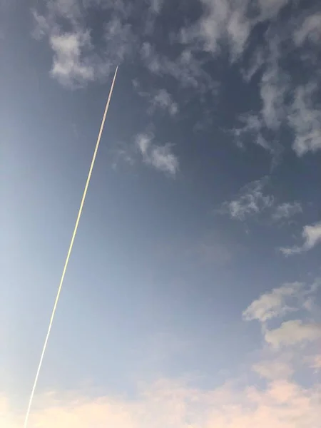 Eine Vertikale Aufnahme Des Kondensstreifen Eines Von Wolken Umgebenen Flugzeugs — Stockfoto