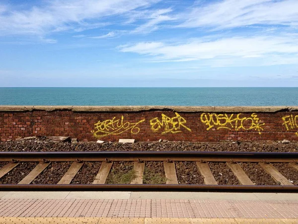 Zid Cărămidă Litere Galbene Fața Liniilor Tren Spatele Oceanului — Fotografie, imagine de stoc