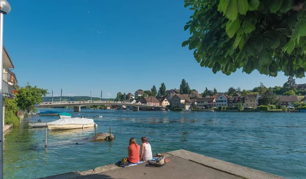 Egy Panoráma Felvétel Két Lányról Akik Egy Partján Ülnek Épületekkel — Stock Fotó