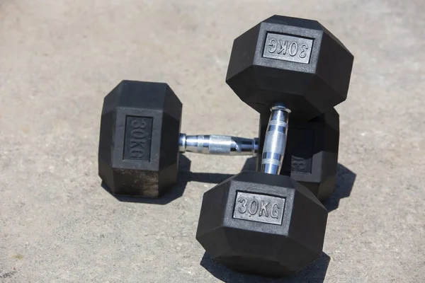 Closeup Shot Two Dumbbells One Placed Top Other Lying Ground — Stock Photo, Image