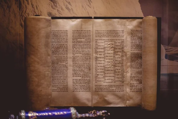 ライトの下のテーブルの上に羊皮紙ロールに書かれたヘブライ語の聖書の閉鎖 — ストック写真