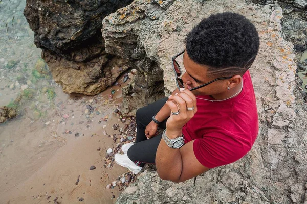 Красивый Снимок Молодого Человека Снимающего Солнечные Очки Сидящего Скалах Озера — стоковое фото