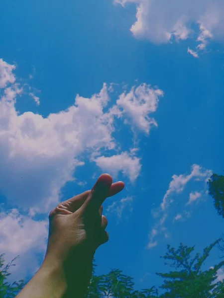 青い空に向かって人の手の垂直ショット — ストック写真