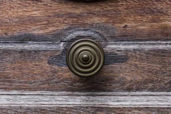 木の扉のツマミの近くにあるツマミは丸青銅で同心円を描いています — ストック写真