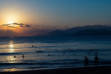A silhouette of people walking on the beach shore in Nha Trang clipart
