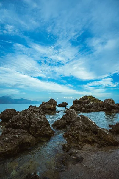 美しい曇り空の下で海による岩の形成の垂直ショット — ストック写真