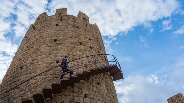 A panoramic shot of a woman climbing up the stairs of the tall fort building