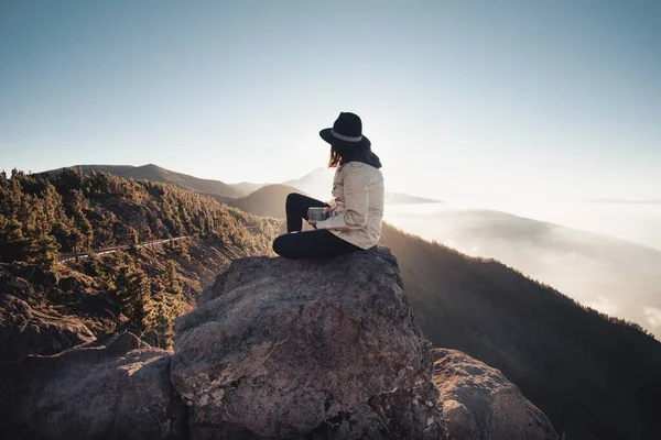 雾蒙蒙的岩石群山的全景 边缘上坐着一顶帽子的女人们 — 图库照片