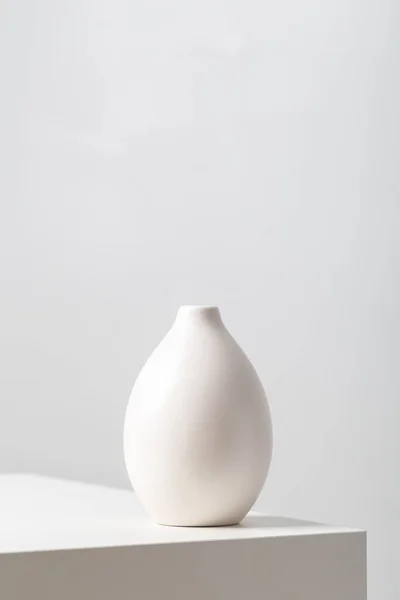 白土花瓶放在桌子上白土花瓶的垂直特写 在白底灯光下 — 图库照片