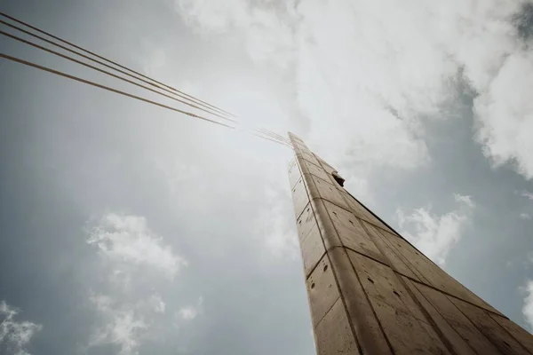 Parlak Bulutlu Bir Gökyüzüne Karşı Kablolu Bir Beton Sütunun Alçak — Stok fotoğraf