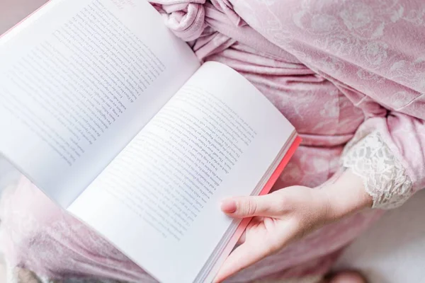 一个穿着粉色连衣裙的女人看英语书的高角照片 — 图库照片