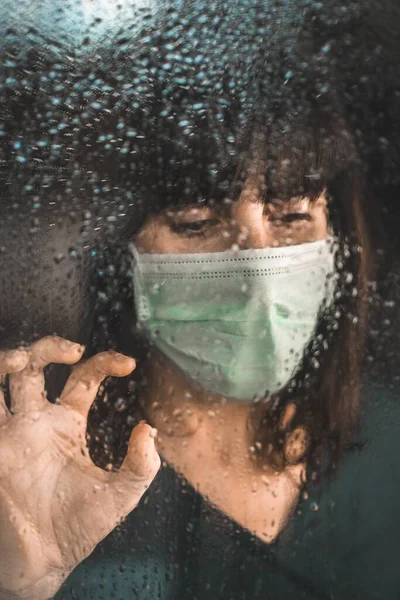 一位戴口罩的年轻女子从窗户向外张望 脸上还带着雨滴 考罗纳维 — 图库照片