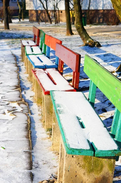 雪に覆われた公園でカラフルなベンチの垂直ショット — ストック写真