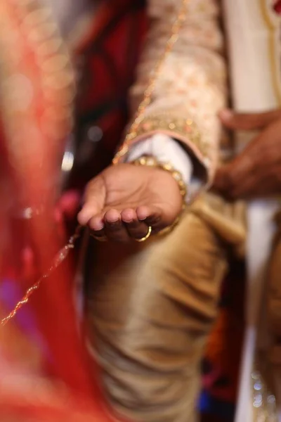 インドの結婚式の間に彼の手を開いて保持黄金のスーツの新郎の垂直閉鎖 — ストック写真