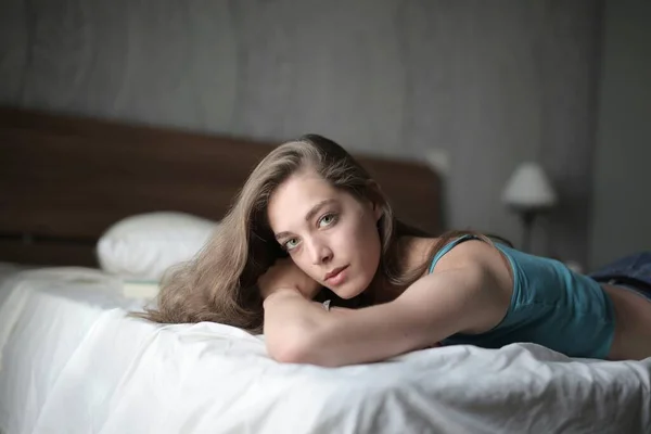 カメラを見ている間にベッドの上に寝そべっている女性の浅いフォーカスショット — ストック写真