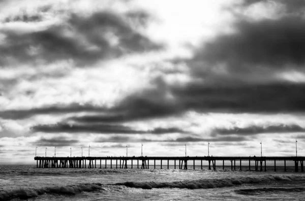 曇り空の下で波状の海に桟橋のグレースケール 背景に最適です — ストック写真