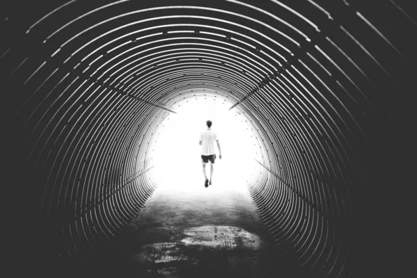 Graustufen Einer Person Die Aus Einem Tunnel Unter Den Lichtern — Stockfoto