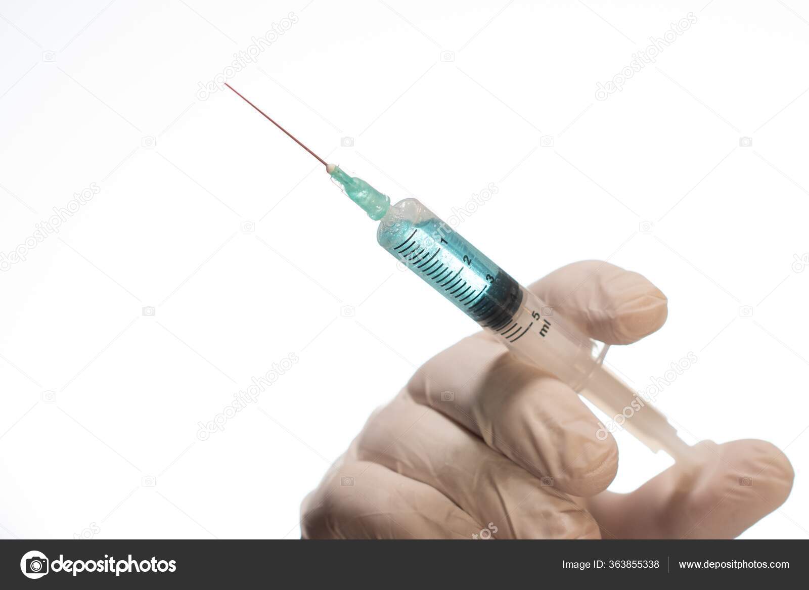 用胶乳手套把针头注射器隔离在白色背景下的人的特写镜头 图库照片 C Wirestock