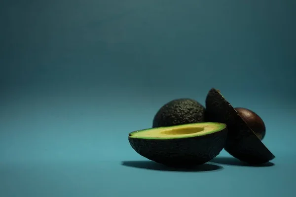 Een Geheel Snijd Verse Avocado Een Blauw Oppervlak — Stockfoto