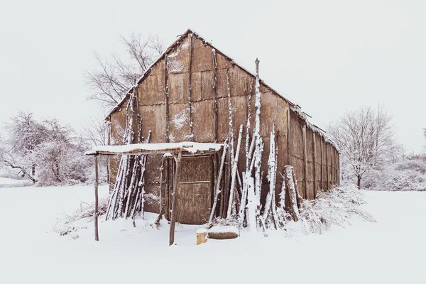 冬の間に白い雪で覆われた地面を持つネイティブアメリカのロングハウス — ストック写真