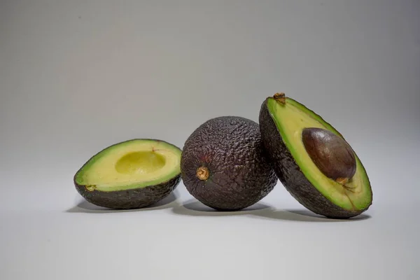 Eine Ganze Und Geschnittene Frische Avocado Auf Einer Grauen Oberfläche — Stockfoto