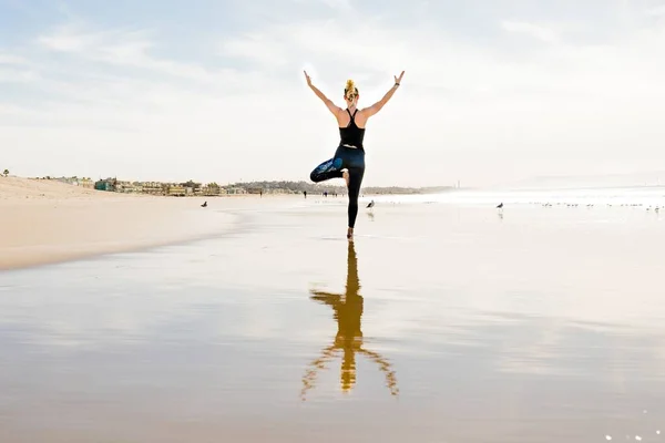 一个漂亮的照片 一个在海滩上摆出瑜伽姿势的女性 — 图库照片