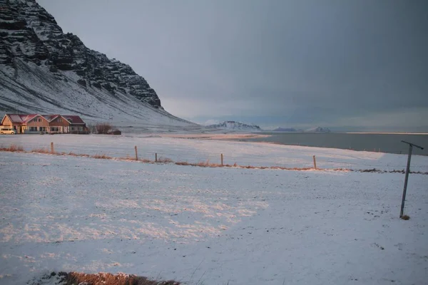 背景には家や山が雪に覆われた穏やかな湖の海岸 — ストック写真