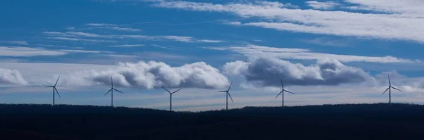 Panoramatický Záběr Větrných Turbín Vrcholu Hory Proti Zamračené Modré Obloze — Stock fotografie