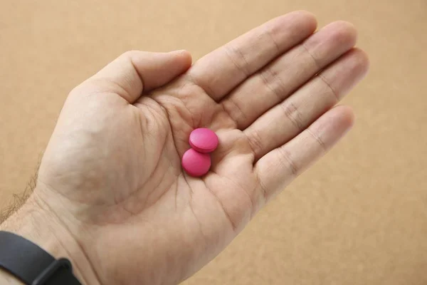 Высокоугольный Снимок Руки Человека Двумя Розовыми Таблетками Розовом Фоне — стоковое фото