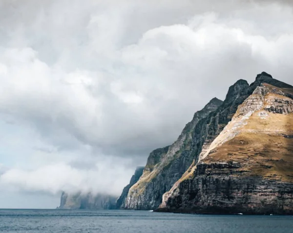 Een Grote Klif Omringd Door Het Water Onder Wolken — Stockfoto