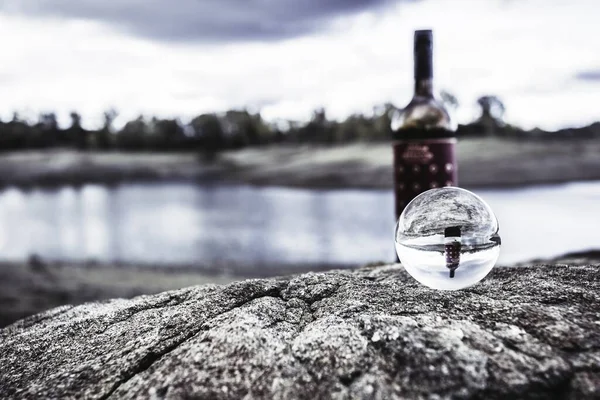 Селективный Фокус Хрустального Шара Камне Отражающий Бутылку Вина Красивое Озеро — стоковое фото