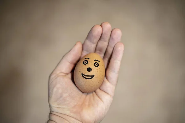 Una Persona Que Tiene Huevo Moreno Con Una Cara Dibujada — Foto de Stock