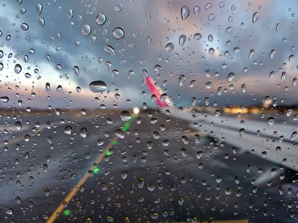 从有雨滴的飞机窗口看到的机场跑道模糊的景象 — 图库照片