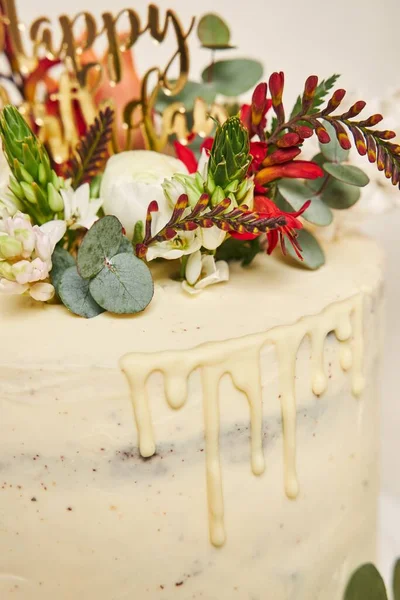 ケーキの上に白いクリームの花が垂直に描かれ サイドにドリップと白い背景があります — ストック写真