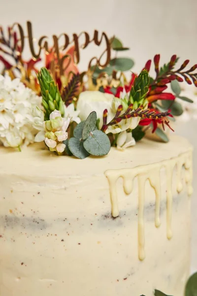 ケーキの上に白いクリームの花が垂直に描かれ サイドにドリップと白い背景があります — ストック写真