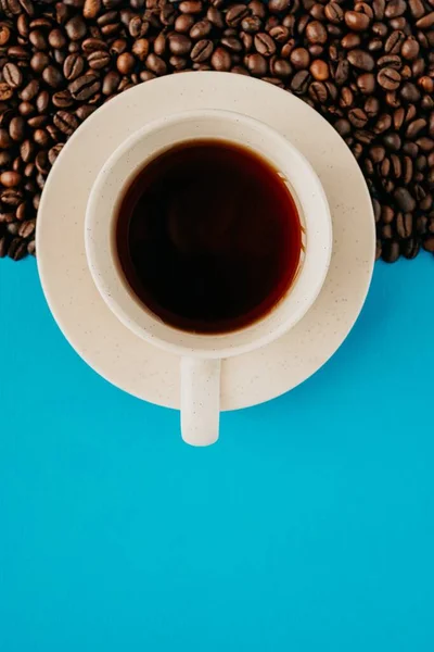 Egy Közeli Kép Egy Csésze Kávé Fölött Kávébabbal Kék Háttérrel — Stock Fotó