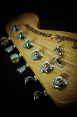 NOTTINGHAM, UNITED KINGDOM - Mar 23, 2020: Close up of fender Stratocaster electric guitar headstock and tuning pegs with 6 strings and fender logo visible clipart