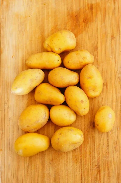Close Vertical Batatas Novas Cruas Uma Placa Corte Madeira — Fotografia de Stock
