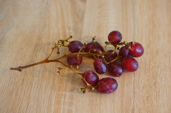 Sebuah Penutupan Setengah Dimakan Anggur Merah Atas Meja Kayu Bawah — Stok Foto