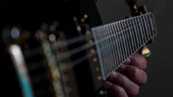 Close Uma Pessoa Tocando Uma Guitarra Elétrica Preta Sob Luzes — Fotografia de Stock