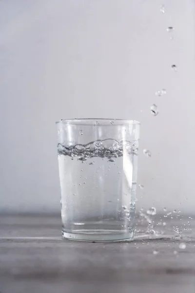Eine Vertikale Aufnahme Eines Glasbechers Mit Wassertropfen Eine Oberfläche — Stockfoto