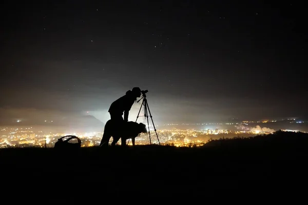 stock image The silhouette of a man a dog and a camera at night