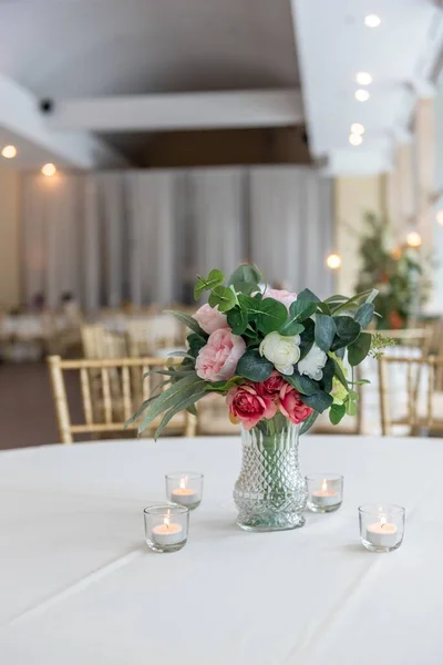 テーブルの上にろうそくに囲まれた美しい花束と花瓶の垂直クローズアップショット — ストック写真